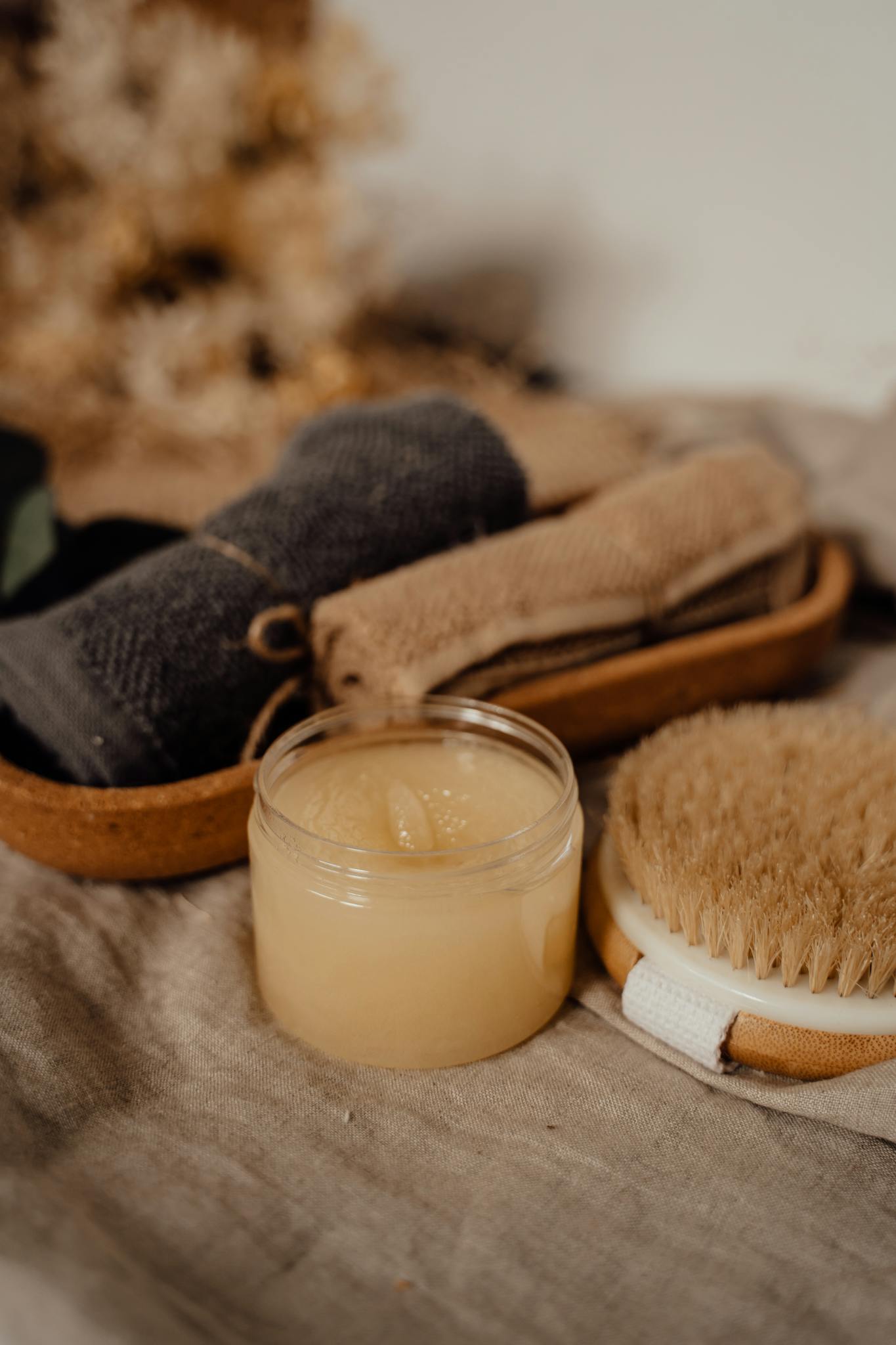 Eco-friendly spa setup with body scrub, brush, and towels for self-care.